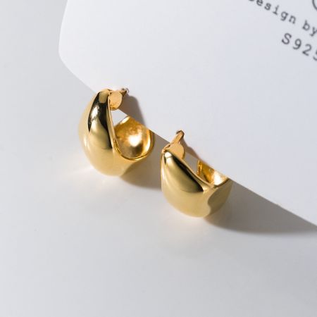 Productafbeelding die een paar gouden S925 sterling zilveren huggie hoop oorbellen toont.