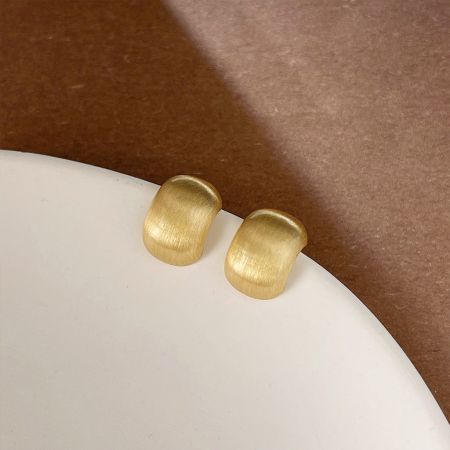 ディスプレイスタンドに置かれた金色のフレンチメタルビーズデザインのスタッドピアス。