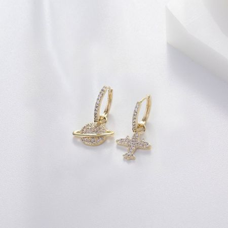 Gros plan sur les boucles d'oreilles Planet Plane Hoop, mettant en avant les détails complexes des charms de Saturne et d'avion.