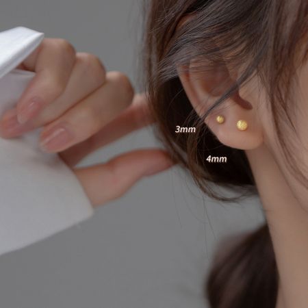 여성의 귀에 3mm 및 4mm 금 더블 볼 스터드 귀걸이를 착용한 클로즈업 사진으로 크기 비교.