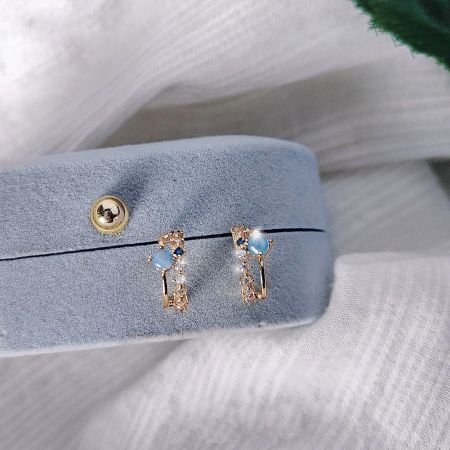 金と青い宝石のスタッドピアスの別の角度で、精巧な職人技を展示しています。