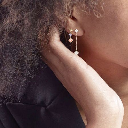 Model showcasing a pair of gold earrings with multiple charms, demonstrating how they look when worn.
