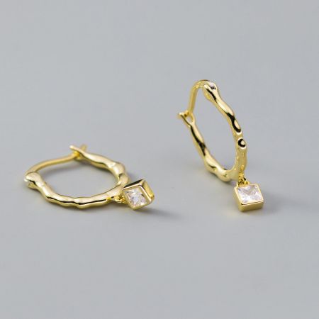 Gros plan de la version luxueuse plaquée or des boucles d'oreilles en zircon à coupe carrée torsadée.