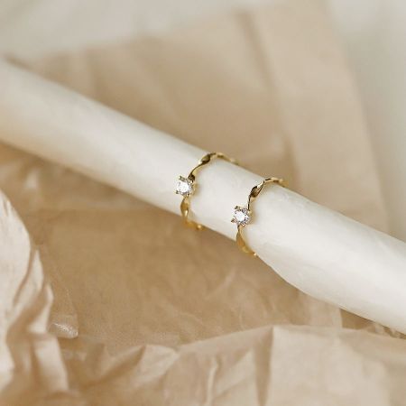 Um par de brincos huggie de ouro elegantes com pedras de zircônia claras, parte da coleção de prata esterlina por atacado.
