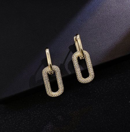 Vue détaillée des boucles d'oreilles pendantes en or mettant en valeur les pierres en zircon cubique transparent.