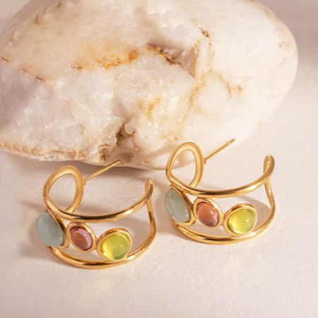 Un par de pendientes de estilo español con vibrantes piedras de ópalo de tres colores sobre un fondo neutro.