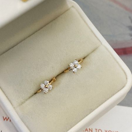 De gouden zircon klavertje vier hoepel oorbellen elegant gepresenteerd in een witte sieraden doos, perfect om cadeau te geven.