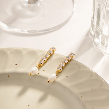 Close-up detail van de zoetwaterparel en cubic zirconia stenen op de vergulde roestvrijstalen oorbellen.