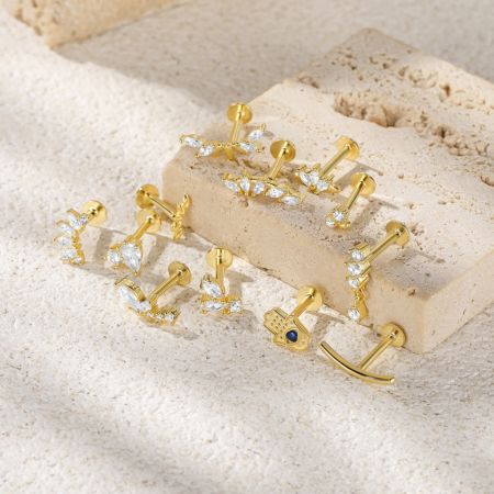 Una esposizione di diversi design di piccoli orecchini a bottone impilabili in argento sterling 925, con varie pietre preziose.