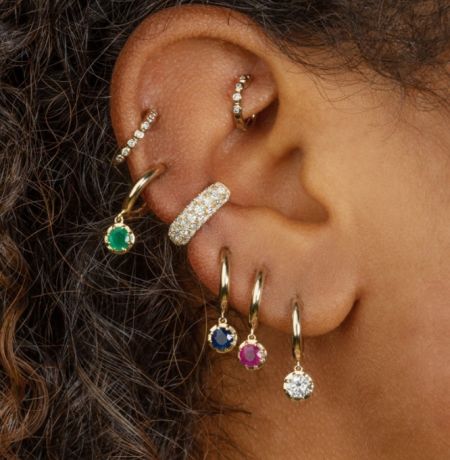 Model showcasing multiple Halo Huggie Drop Earrings with colorful gemstones on the ear.