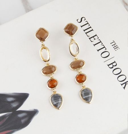 Primer plano de los pendientes de gota de resina chapados en oro que muestran los detalles de las piedras preciosas.