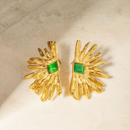 Een paar gouden oorbellen met groene edelstenen in een abstract bloemachtig ontwerp.