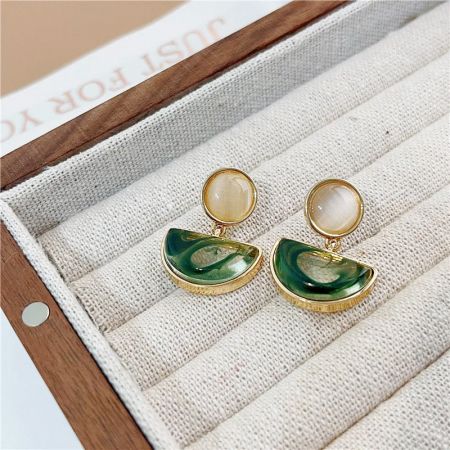 オフホワイトの丸い石と緑のハーフムーンストーンをあしらった金のイヤリング。
