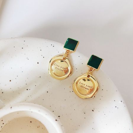 Un autre angle des boucles d'oreilles en émail doré et vert avec une gravure inspirante.