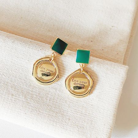 Vue d'ensemble du set de boucles d'oreilles plaquées or avec des pierres vertes et des pendentifs 'Vivez votre rêve'.