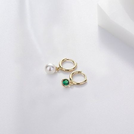 Side view of the pearl and emerald huggie hoop earrings showcasing the gold plating.