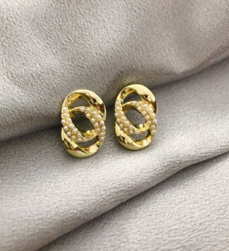 Detalle en primer plano de los pendientes de perlas con eslabones cubanos chapados en oro con acentos de perla.