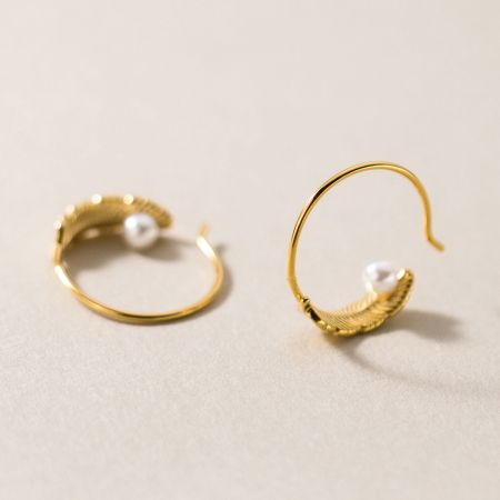 Scatto dettagliato della superficie testurizzata in oro e della perla sull'orecchino a cerchio C.