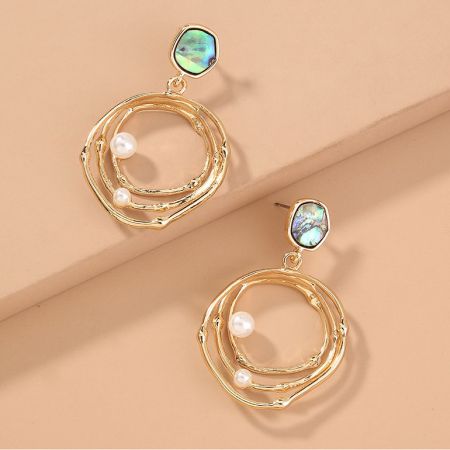 パールと虹色の石のディテールを強調した、円形デザインのゴールドフープイヤリングのクローズアップビュー。