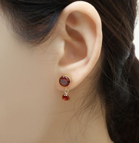 Scatto di dettaglio degli orecchini a bottone abbinati con pietre in zirconia cubica rosso fuoco.