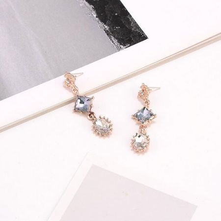 Vue de côté des boucles d'oreilles géométriques pendantes montrant les facettes des pierres précieuses.