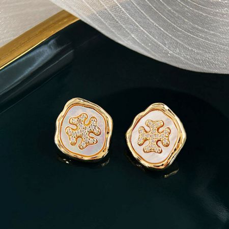 花のデザインに繊細な白とピンクのインレイが施された金のピアスのペア。