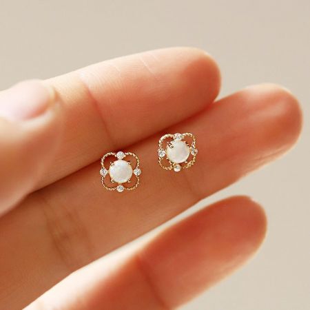 Een paar minimalistische sterling zilveren opaal oorbellen tegen een schone witte achtergrond.