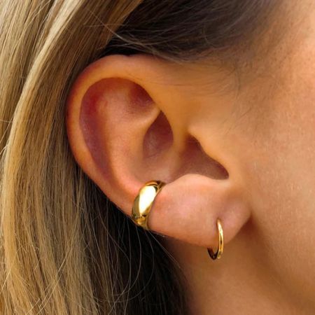 Una donna indossa il bracciale auricolare a forma di C in oro.
