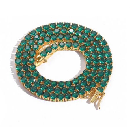Luxurious gold-toned tennis bracelet with striking green emerald-like stones.