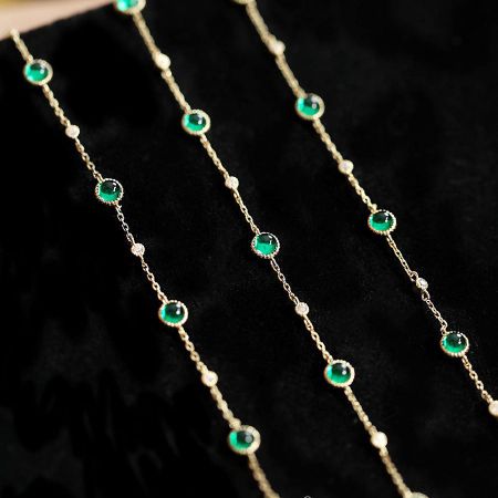 Pulseras de cadena de esmeralda y circonio de plata esterlina 925 al por mayor (conjunto de 5) - Un conjunto al por mayor de pulseras de cadena de plata esterlina 925 con piedras de esmeralda y circonio, elegantemente exhibidas en un soporte de terciopelo negro.