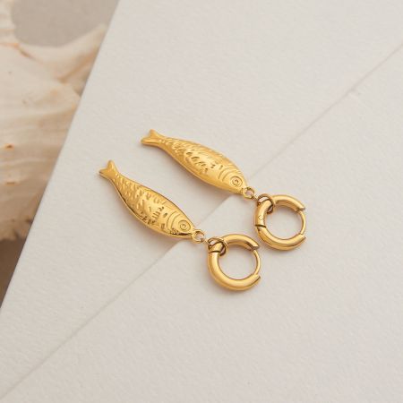 Primo piano degli orecchini a forma di pesce d'oro con anelli circolari, evidenziando il design intricato.