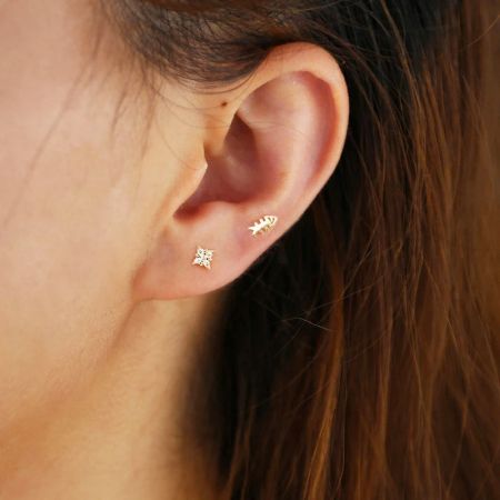 Modello che indossa l'orecchino a stella ottagonale dorato insieme ad altri stili.