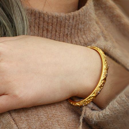 金の天体テーマのオープンカフブレスレットを着用したモデル。