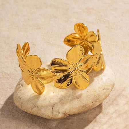 Detaillierte Ansicht des goldenen Blumenarmbands auf einem Steindisplay.
