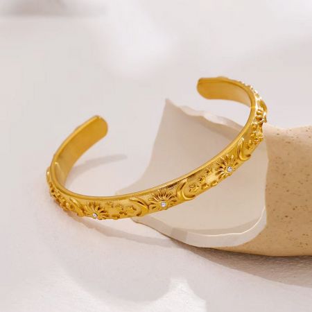 金のカフブレスレットに施されたキラキラと輝くキュービックジルコニアの宝石のクローズアップ。