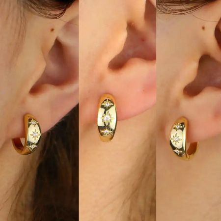 Vista dettagliata di un singolo orecchino huggie a cerchio in oro con CZ a forma di stella, evidenziando gli accenti di diamante.