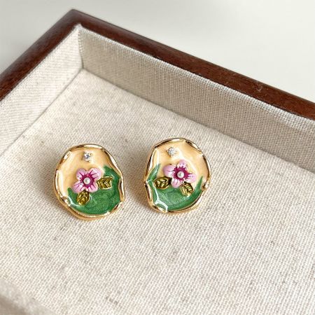 精巧なエナメルとラインストーンのディテールを持つスタイリッシュな手作り風の金の花のイヤリングのペア。