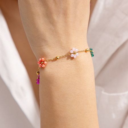 Roestvrijstalen kleurrijke bloemencharms kettingarmbanden set van 5. - Een close-up van een goudkleurige roestvrijstalen armband uit de set, met delicate bloemencharms en kleurrijke edelsteenkralen.