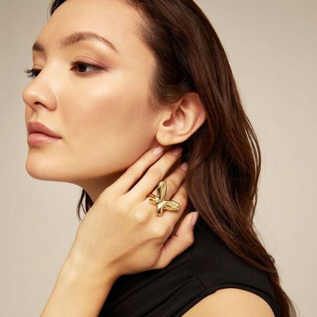 Uma mulher exibindo o elegante anel dourado inspirado em flores em seu dedo.