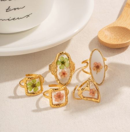 Uma coleção de cinco anéis de ouro com vários designs florais, exibindo o estilo de JR Fashion Accessories.