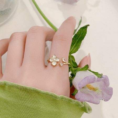 A model's hand wearing a charming gold ring with a flower and bow design from the collection.