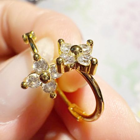 Een macro-opname van een enkele klavertje oorbel, die het ingewikkelde detail van de 18K gouden plating en zircon zetting toont.