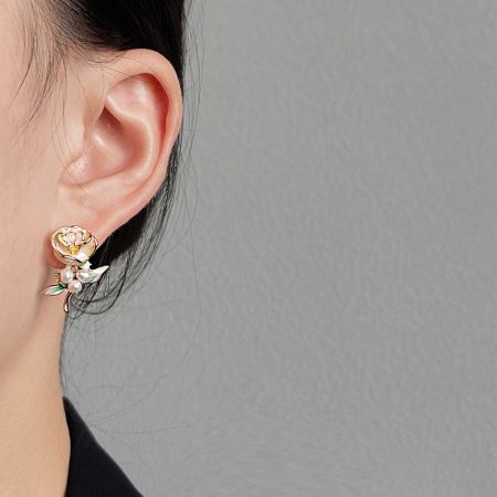 真珠のアクセントが付いたヴィンテージ金メッキのバラの花のイヤリングを着用したモデル。