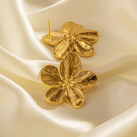 Elegant gold blossom earrings showcased on a luxurious cream satin background.