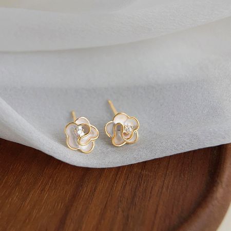 Vue détaillée des boucles d'oreilles en fleur plaquées or, mettant en valeur la pierre précieuse claire.