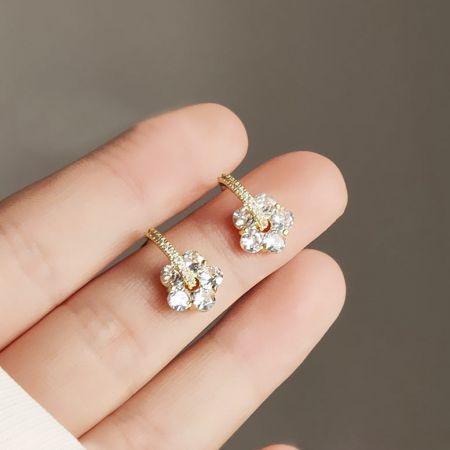 ジルコンクリスタルのディテールを展示した金メッキの花のイヤリングの上からのビュー。