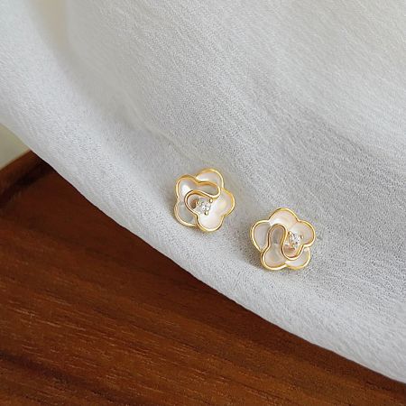 Photo produit des boucles d'oreilles en fleur plaquées or avec des accents de zircon scintillants sur un fond texturé.