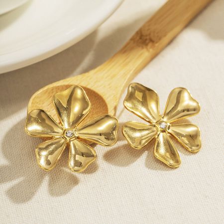 Detailopname van de gouden bloemenoorbellen met de centrale diamantaccenten.