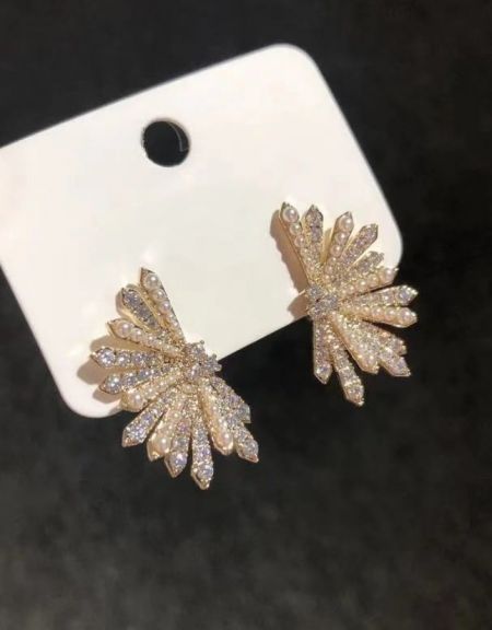 A close-up shot of the gold-toned pearl fan earrings, emphasizing the sparkle of the embedded crystals.