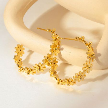 Zijprofiel van de gouden bloemen C-vormige hoepel-studoorbellen.